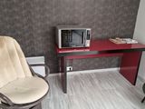 a small desk with a chair and a microwave on it