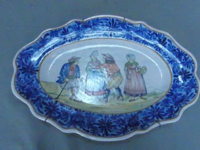 une assiette bleue et blanche sur laquelle est représenté un groupe de personnes