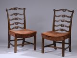 deux chaises en bois avec des assises recouvertes de cuir, posées sur une surface blanche