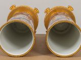 pair of gold and white vases on a table with a brown background
