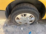 a yellow car with a flat tire on the street