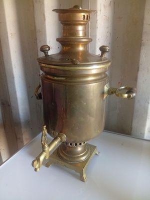 une petite cafetière en laiton posée sur une table blanche