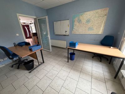 une pièce avec un bureau, des chaises et une carte accrochée au mur