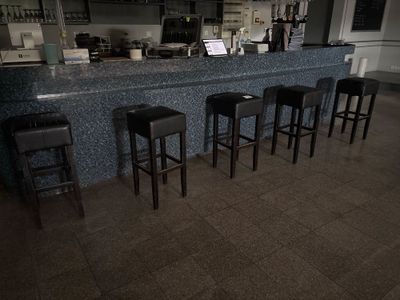 quatre tabourets devant un bar, avec un ordinateur portable posé sur le comptoir