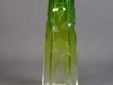 un vase en verre vert posé sur une surface blanche