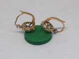 pair of gold and diamond earrings on a green base