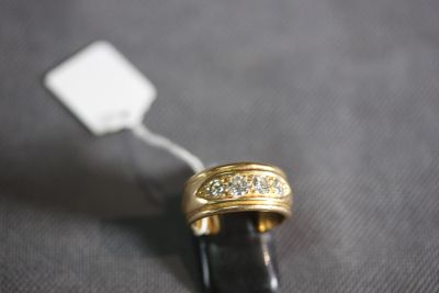 a gold ring with diamonds on it on a black surface