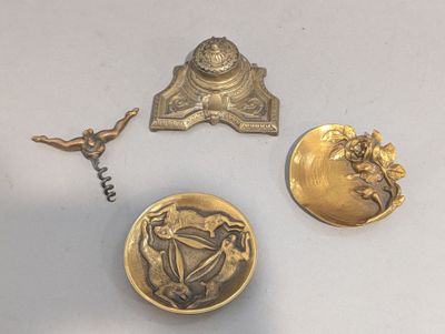 trois boutons anciens en laiton et un décapsuleur posés sur une surface blanche