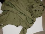 a green jacket laying on the floor next to a pair of shoes