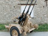 a military vehicle with two guns on it parked in front of a building