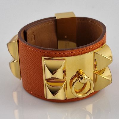bracelet en cuir orné de clous dorés et d'un anneau sur fond blanc
