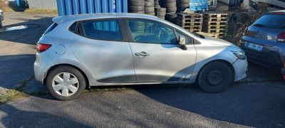 une voiture argentée garée à côté d'un tas de pneus