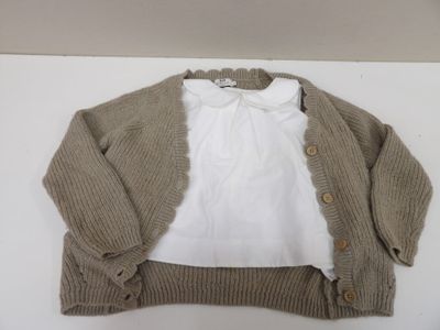 une chemise blanche et un gilet marron posés sur une table
