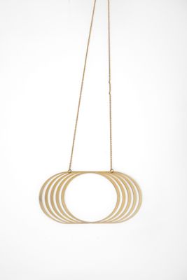 a gold necklace hanging from a gold chain with a circular design