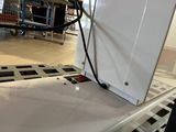 a white refrigerator sitting on top of a conveyor belt in a store