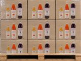 Des cartons de jus de fruits sont posés sur des palettes dans un entrepôt, avec d'autres palettes en arrière-plan