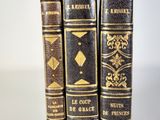 three old books sitting on top of each other on a white surface
