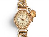 a gold watch with a chain around it on a white surface
