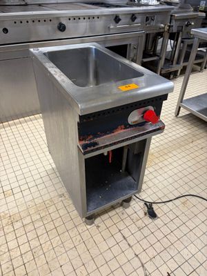 un évier au milieu d'une cuisine, avec en arrière-plan de nombreux appareils électroménagers en inox