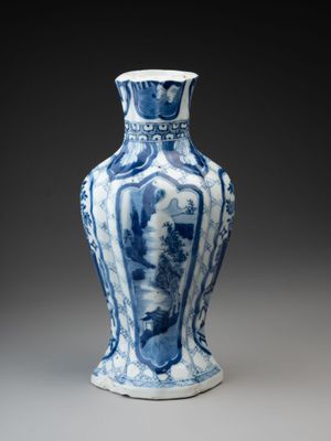 blue and white vase on a gray surface with a black background