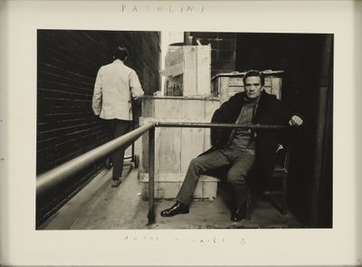 photographie en noir et blanc d'un homme assis sur un banc près d'une balustrade