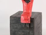 statue of a woman sitting on a block with her hands behind her head