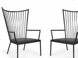 a pair of black chairs sitting next to each other on a white surface