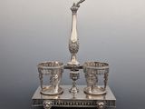 a silver plate with three cups and a vase on a stand