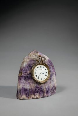 horloge en marbre violet posée sur un socle, avec un cadran plaqué or
