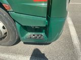 a green truck parked in a parking lot with its door open