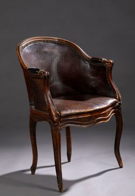 un fauteuil en cuir marron posé sur un sol gris