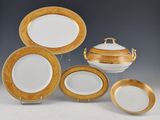 a group of gold and white dinner plates and a casserole dish