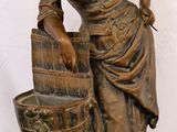 bronze statue of a woman with a bucket of water on a black surface
