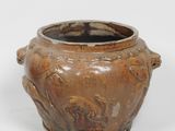 un vase brun posé sur une surface blanche