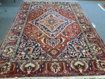 un tapis posé à même le sol dans une pièce, avec une chaise à l'arrière-plan