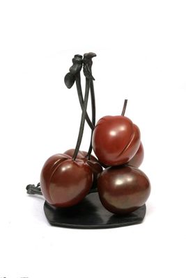 three cherries sitting on top of each other on a black plate