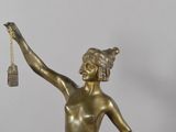bronze statue of a woman holding a bell and a bell hanging from a chain
