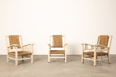 trois chaises dans une pièce aux murs blancs et au sol en béton