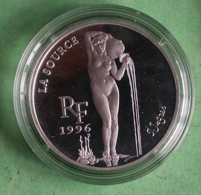 a close up of a silver coin with a nude woman on it