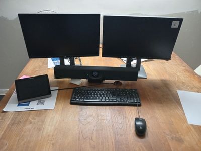 two computer monitors and a keyboard on a wooden desk