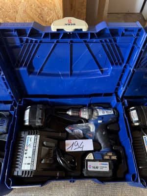 Deux outils électriques se trouvent dans une boîte bleue posée par terre.