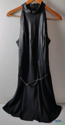 a black dress hanging on a hanger on a wall