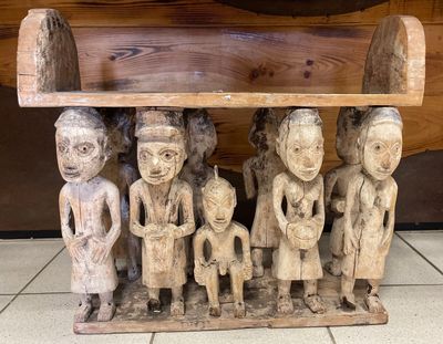 un banc en bois sur lequel est représenté un groupe de personnages sculptés