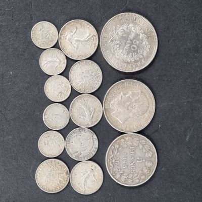 quelques pièces d'argent posées sur une surface noire, en petit nombre