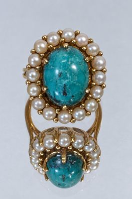 a close up of a ring with pearls and a turquoise stone