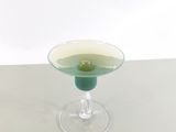 a glass with a green olive in it sitting on a table