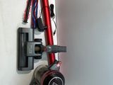 a red vacuum that is on the wall next to a brush