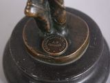 a bronze figurine of a man holding a baseball bat