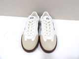 white sneakers with brown soles on a white surface with a white background