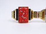 a gold bracelet with a red stone in the middle